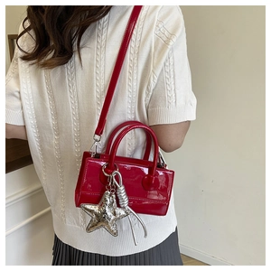 Back view of model wearing vibrant red patent leather crossbody bag with silver star charm