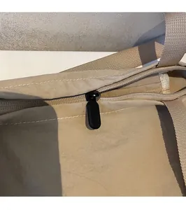 Close-up of smooth black metal zipper head and durable stitching on beige tote bag