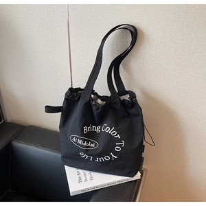 Detailed view of black drawstring tote bag with white round print on a designer book