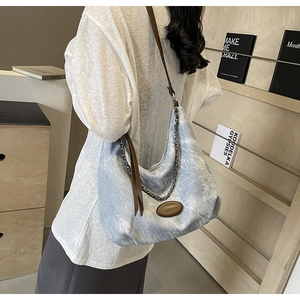 Detailansicht der Denim Hobo-Tasche mit Kettenriemen und strukturiertem Stoff am Modell