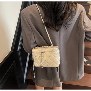 Detail of cream quilted crossbody bag with sparkling rhinestones and rose pendant