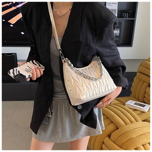 Modische cremeweiße Hobo-Tasche mit Falten, Silberkette und Lederriemen am Model getragen