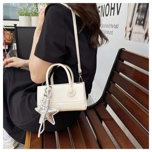 Off-white crossbody bag with silver star charm shown on a model in an outdoor setting