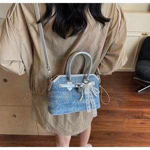 Détail du sac bandoulière en denim avec nœud en dentelle et perle sur un mannequin
