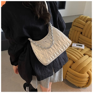 Detailansicht eines Modells mit beiger gesteppter Hobo-Tasche und silberner Kette
