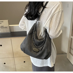 Detail view of large black denim crossbody bag with silver chain and adjustable strap