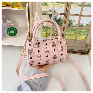 Detailed macro of pink cylinder handbag featuring bear print and gold hardware