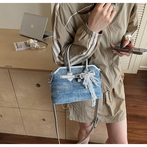 Sac coque en denim bleu avec bordure en cuir argenté, fermoir métal et nœud dentelle