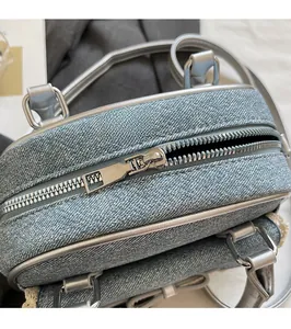 Detail of silver metal zipper on light blue denim shell bag with sleek fabric texture