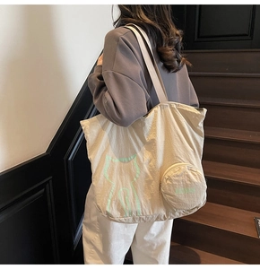 Détail du sac cabas en nylon beige avec motif chat et pochette ronde sur l'épaule