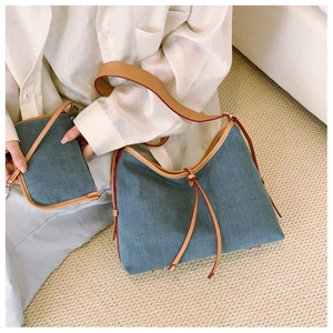Detail of blue denim hobo tote with red-brown leather trim and matching pouch