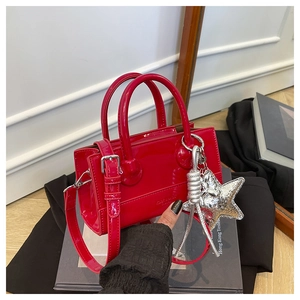Detail of red patent leather handbag with dual handles and silver star charm