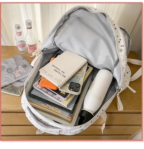 Open view of white star pattern backpack showing large storage capacity for laptop and books