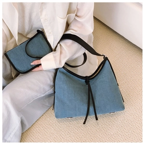 Detail of light blue denim tote and matching pouch with black leather piping and straps