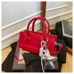 Detail of red glossy patent leather handbag with a silver star charm and stylish dual handles