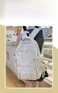 Detail view of a white backpack with black stars pattern and cute plush charms