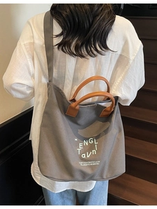 Grand sac fourre-tout en toile grise avec poignées en cuir marron et bandoulière réglable