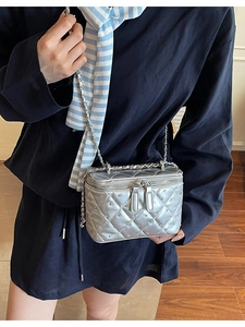 Silver quilted metallic vanity bag with chain strap shown on a cross-body model