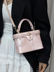 Pink vintage box style handbag with gold rivets and decorative strap on model