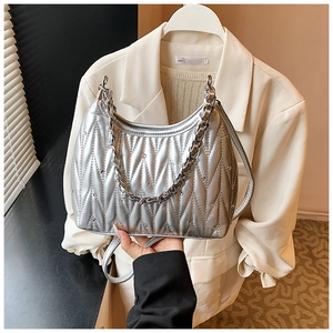 Detail der silbernen Metallic-Sichel-Tasche mit Steppmuster und kleinen Nietennieten