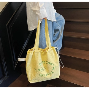 Close-up of yellow drawstring canvas tote with Bring Color To Your Life green slogan