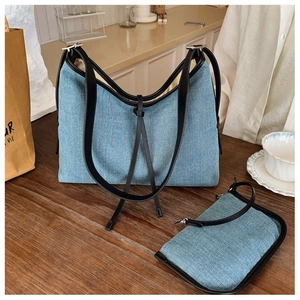 Detail of light blue denim tote bag with black leather trim and matching small clutch