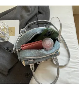 Internal view of blue denim shell bag showing capacity for phone, wallet and cosmetics