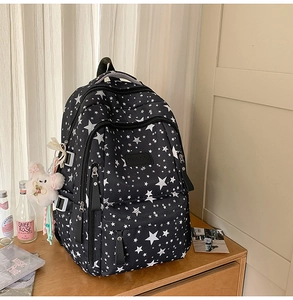 Detail of star pattern black backpack with multiple pockets and plush bunny charm