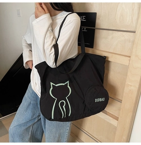 Detail of a black large tote bag featuring a green cat outline and matching round coin purse