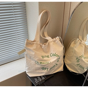 Detail of cream canvas tote bag with green Bring Color To Your Life text and drawstring