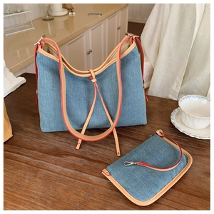 Detail of denim tote set with brown leather straps and orange edge paint finish