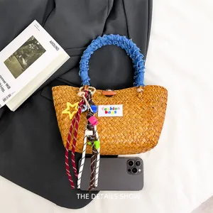 Detailed straw woven bag with blue denim round handles and colorful bead charms