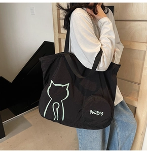 Détail d'un grand sac cabas noir pliable avec contour de chat vert et poche ronde
