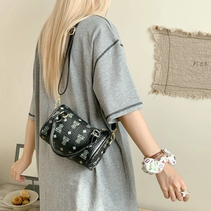 Detail of black cylindrical pillow bag with green bear pattern and gold metal hardware