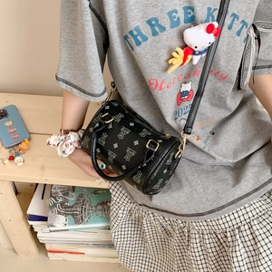 Detail of black cylindrical crossbody bag with bear pattern and gold-tone zipper