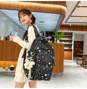 Detail of star pattern black backpack on model in a cozy cafe setting