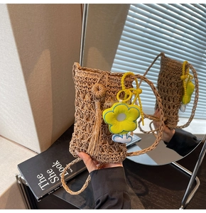 Dettaglio della borsa a tracolla in paglia intrecciata a mano con ciondolo a fiore giallo