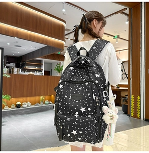 Close-up of black canvas backpack with white star patterns and cute plush rabbit charm