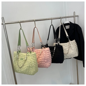 Detail of puffed texture tote bags in green, pink, black, and white with pearl chain straps