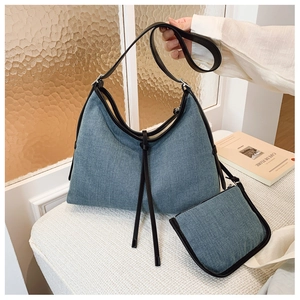 Detail of denim tote bag with matching pouch and black leather fringe on soft white bench