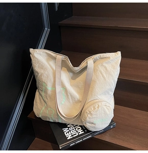 Detail of beige canvas tote bag with green cat print and matching small round pouch