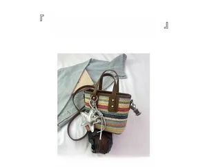 Detail of colorful striped straw bucket bag with brown leather strap and star charm
