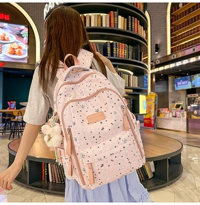 Detail view of pink backpack with star patterns and multiple functional zip compartments
