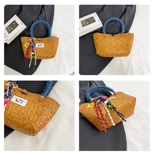 Detail of hand-woven straw beach bag featuring denim handles and colorful tassels