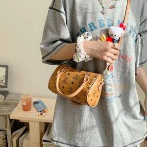 Detail of a brown Boston bag with teddy bear pattern and leather handles shown on a model