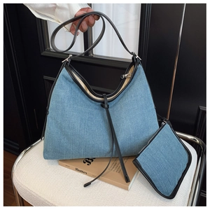 Detail of light blue denim tote set with black leather trim and matching small pouch
