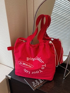 Red canvas drawstring tote bag with Bring Color To Your Life text on black surface