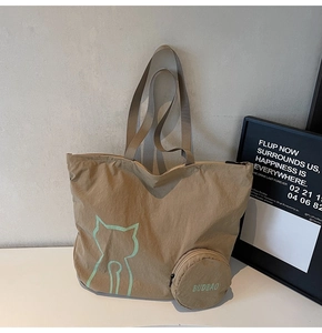 Macro detail of khaki foldable tote bag with green cat silhouette and round coin pouch