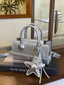 Silver metallic crossbody bag with star charm on black book in elegant interior