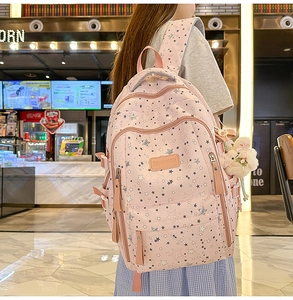 Close-up of pink star print backpack featuring multiple zipper pockets and a plush bunny